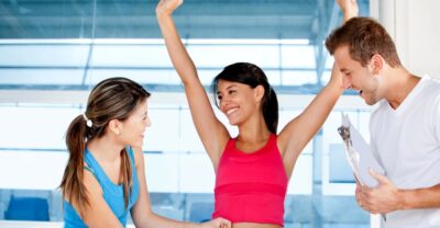 Happy-woman-at-the-gym-with-her-trainers-measuring-her-body-_-weight-loss